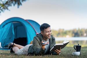 uomo leggere libro mentre viaggiatore con campeggio. concetto di moderno persone stile di vita nel Lavorando foto