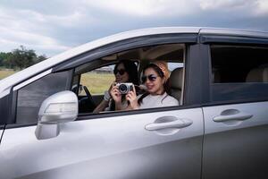 giovane contento asiatico ragazza amici ridendo e sorridente nel auto durante un' strada viaggio per vacanza foto