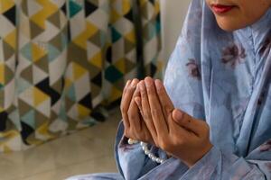 un' musulmano donna indossare musulmano Abiti con hijab chiamato mukena e raccolta sua mani per preghiere foto
