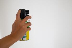 mano Tenere un aerosol può di insetticida. zanzara o insetto spray con bianca sfondo. foto