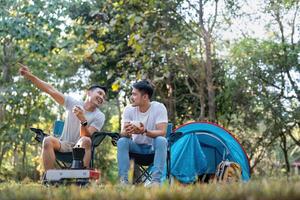 maschio gay coppia asiatico in viaggio con tenda campeggio all'aperto e vario avventura stile di vita escursioni a piedi attivo estate vacanza. potabile caffè e parlando insieme foto