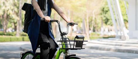 asiatico donna d'affari nel bicicletta partire per opera a ufficio. bicicletta pendolarismo, contento donna d'affari utilizzando eco trasporto, concetto di eco stile di vita foto