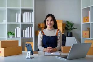 avviare pmi piccolo attività commerciale imprenditore pmi o libero professionista asiatico donna utilizzando un' il computer portatile con scatola, giovane successo asiatico donna in linea marketing pacchetto scatola e consegna concetto foto