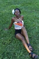 giovane nero donna seduta su erba parco foto