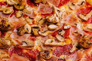 Pizza con prosciutto, salame e funghi vicino su foto