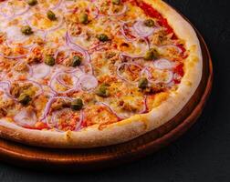 delizioso Pizza tonno con pomodori, olive, cipolla e capperi foto