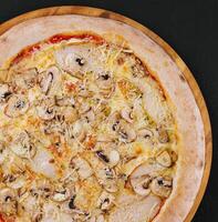 Pizza con prosciutto e funghi su un' di legno tavola foto
