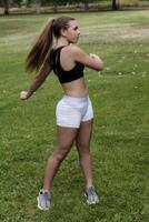 caucasico adolescente ragazza esercizio nel parco indossare bianca pantaloncini nero superiore foto