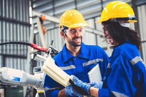 ingegneri squadra meccanico utilizzando computer controllore robotica braccio per saldatura acciaio nel acciaio fabbrica officina. industria robot programmazione Software per automatizzato produzione tecnologia foto