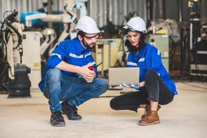 ingegneri squadra meccanico utilizzando computer controllore robotica braccio per saldatura acciaio nel acciaio fabbrica officina. industria robot programmazione Software per automatizzato produzione tecnologia foto