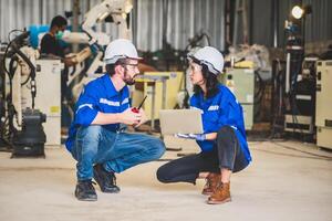 ingegneri squadra meccanico utilizzando computer controllore robotica braccio per saldatura acciaio nel acciaio fabbrica officina. industria robot programmazione Software per automatizzato produzione tecnologia foto