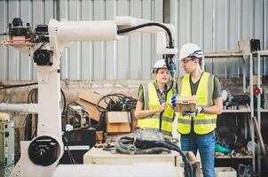 ingegneri squadra meccanico utilizzando computer controllore robotica braccio per saldatura acciaio nel acciaio fabbrica officina. industria robot programmazione Software per automatizzato produzione tecnologia foto