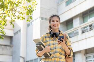 bellissimo alunno asiatico donna con zaino e libri all'aperto. Sorridi ragazza contento trasporto un' lotto di libro nel Università città universitaria. ritratto femmina su internazionale Asia Università. formazione scolastica, studia, scuola foto