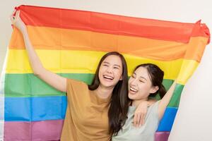 lgbt gruppo. bene guardare lesbica coppie Sorridi brillantemente copertina arcobaleno bandiere. asiatico giovane coppia abbracciare ogni altro felicemente, amante nel amore, bisessualità, omosessualità, libertà, espressione, contento vita foto