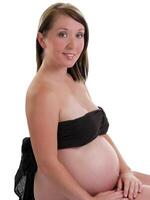 giovane incinta donna seduta con spoglio pancia foto