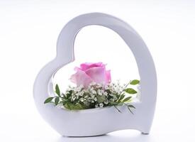 un' bianca ceramica cuore sagomato vaso con rosa Rose foto