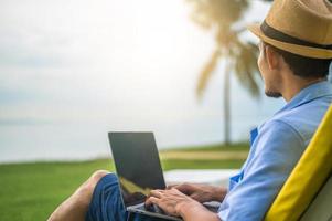 L'uomo che utilizza il computer portatile sulla spiaggia mare e uomo viaggio vacanza phuket island sandbox thailandia sono libertà vita finanziaria