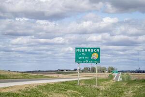 Nebraska, il bene vita, casa di pergolato giorno - ciglio della strada benvenuto cartello a stato confine con Kansas, primavera scenario foto