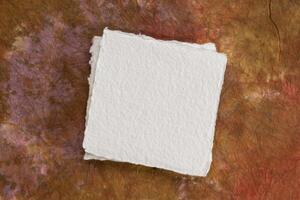 piccolo piazza foglio di vuoto bianca khadi carta contro colorato marmorizzato carta foto