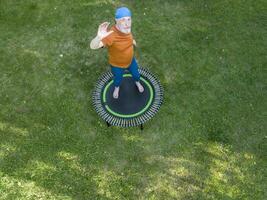anziano sovrappeso maschio esercizio su un' mini trampolino nel il suo Giardino dietro la casa Giardino dietro la casa, fitness e rimbalzante concetto, aereo Visualizza foto