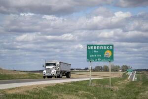 Nebraska, il bene vita, casa di pergolato giorno - ciglio della strada benvenuto cartello a stato confine con Kansas, primavera scenario foto