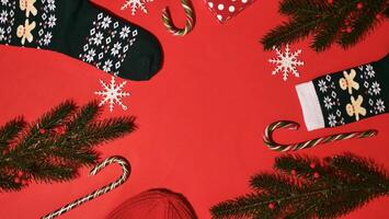 festivo Natale telaio su rosso sfondo su nuovo anno 2024 con ramo, regalo, cappello, caramella caramello, fiocchi di neve, calzini. superiore Visualizza, avvicinamento, piatto, copia spazio, composizione foto