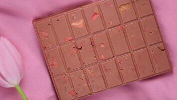 un' bar di rosa rubino cioccolato con sublimato liofilizzato fragole e mandorle e primavera tulipano fiori . un' dolce basato su frutti di bosco e noccioline per internazionale Da donna giorno, marzo 8, La madre di giorno foto