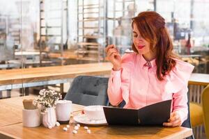 affascinante giovane donna nel rosa camicia godendo mangiare prima colazione a bar. foto