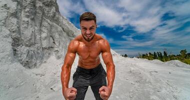 bodybuilder con Perfetto, le spalle, bicipite, tricipiti e il petto in posa all'aperto su sfondo di blu cielo. forte, atletico uomo in piedi con nudo torso. concetto di bellissimo salutare corpo. foto