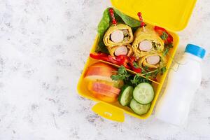 scuola pranzo scatola con salsiccia rotolo nel frittata con lavash. sacco per il pranzo. cheto il pranzo. superiore Visualizza, piatto posare foto