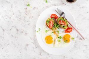 cheto prima colazione. fritte uova e crostini con guacamole e pomodori. superiore Visualizza, piatto posare foto