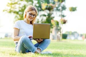 attraente ragazza con un' il computer portatile nel il parco foto