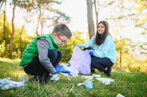 donna volontario e poco ragazzo raccolta su il plastica spazzatura foto