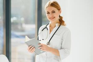 ritratto di giovane donna medico con bianca cappotto in piedi nel Ospedale. foto
