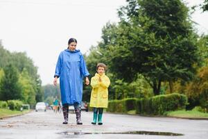 mamma e figlio nel impermeabili avere divertimento insieme nel il pioggia. concetto di famiglia vacanza e contento infanzia. foto