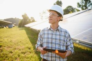 il ritratto di un' giovane ingegnere controlli fotovoltaico solare pannelli. concetto rinnovabile energia, tecnologia, elettricità, servizio, verde potenza. foto