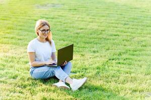 bella giovane donna fare surf Internet su il computer portatile all'aperto. foto