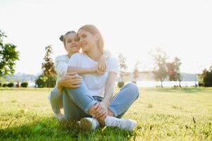 contento madre e figlia rilassante nel il parco. bellezza natura scena con famiglia all'aperto stile di vita a primavera o estate volta. contento elegante famiglia riposo insieme, avendo divertimento all'aperto. foto