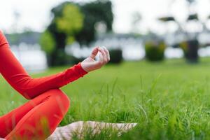 vicino su di giovane donna fare yoga nel il parco con tramonto foto