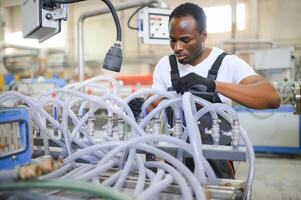 ritratto di africano americano maschio ingegnere nel uniforme e in piedi nel industriale fabbrica foto