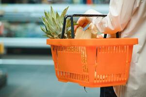 saldi, acquisti, consumismo e persone concetto - donna con cibo cestino a drogheria memorizzare o supermercato foto