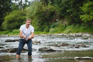 barbuto uomo attraente pesce. estate tempo libero. maturo uomo pesca su il stagno. ritratto di allegro anziano uomo pesca. maschio pesca. pescatore uncinetto rotazione in il fiume in attesa grande pesce foto