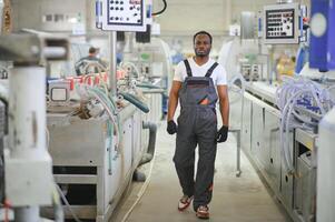 industriale lavoratore in casa nel fabbrica. giovane tecnico con arancia difficile cappello foto