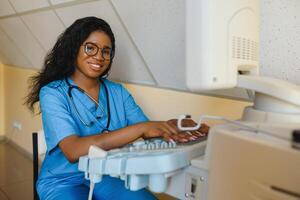 sorridente africano donna medico con ultrasuono scanner nel mano, Lavorando su moderno ultrasuono lettura macchina nel leggero camera nel clinica. ritratto di 4d ultrasuono lettura macchina operatore foto