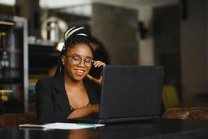 giovane africano americano donna ubicazione a bar Lavorando su il computer portatile foto