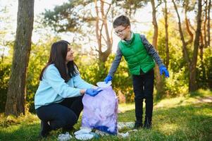 donna volontario e poco ragazzo raccolta su il plastica spazzatura foto