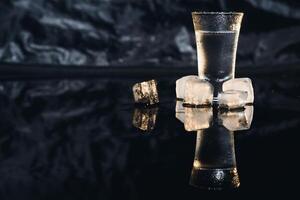 Vodka scatti con ghiaccio su nero tavolo, copia spazio. foto