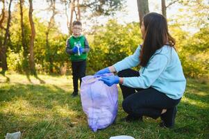 mamma insegna sua figlio per pulito su spazzatura nel natura. un' donna rimuove plastica bottiglie nel un' Borsa. il argomento di ambientale inquinamento di spazzatura. foto