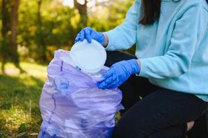 mano mette plastica detriti nel il spazzatura Borsa nel il parco foto