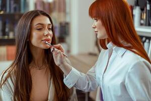 professionale trucco artista l'applicazione lucidalabbra per il femmina cliente labbra nel bellezza salone foto